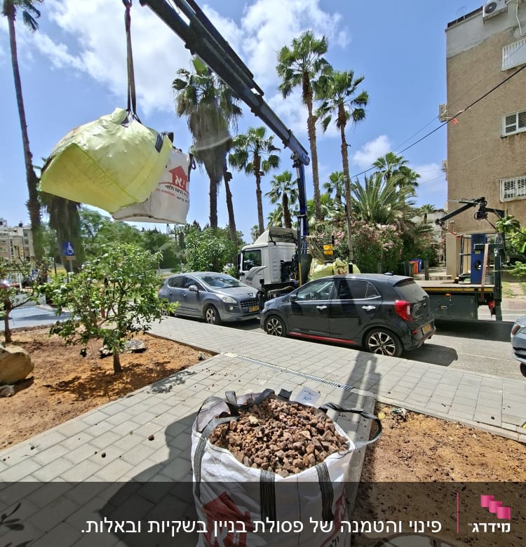 מנוף מרים שק כבד ברחוב עם עצים ומכוניות